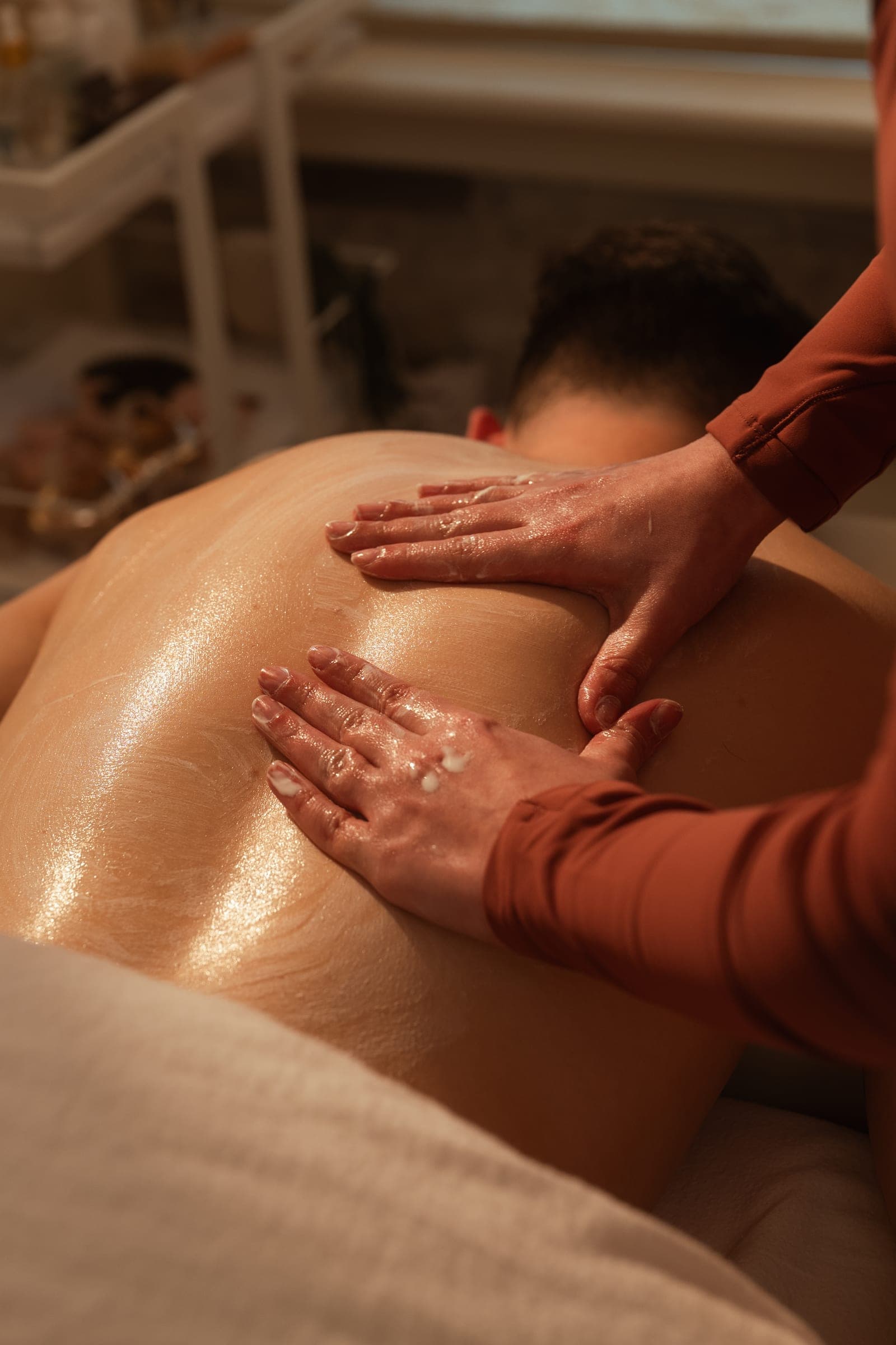 Oiled hands working across a guest's back during the Resèt Back Ritual.