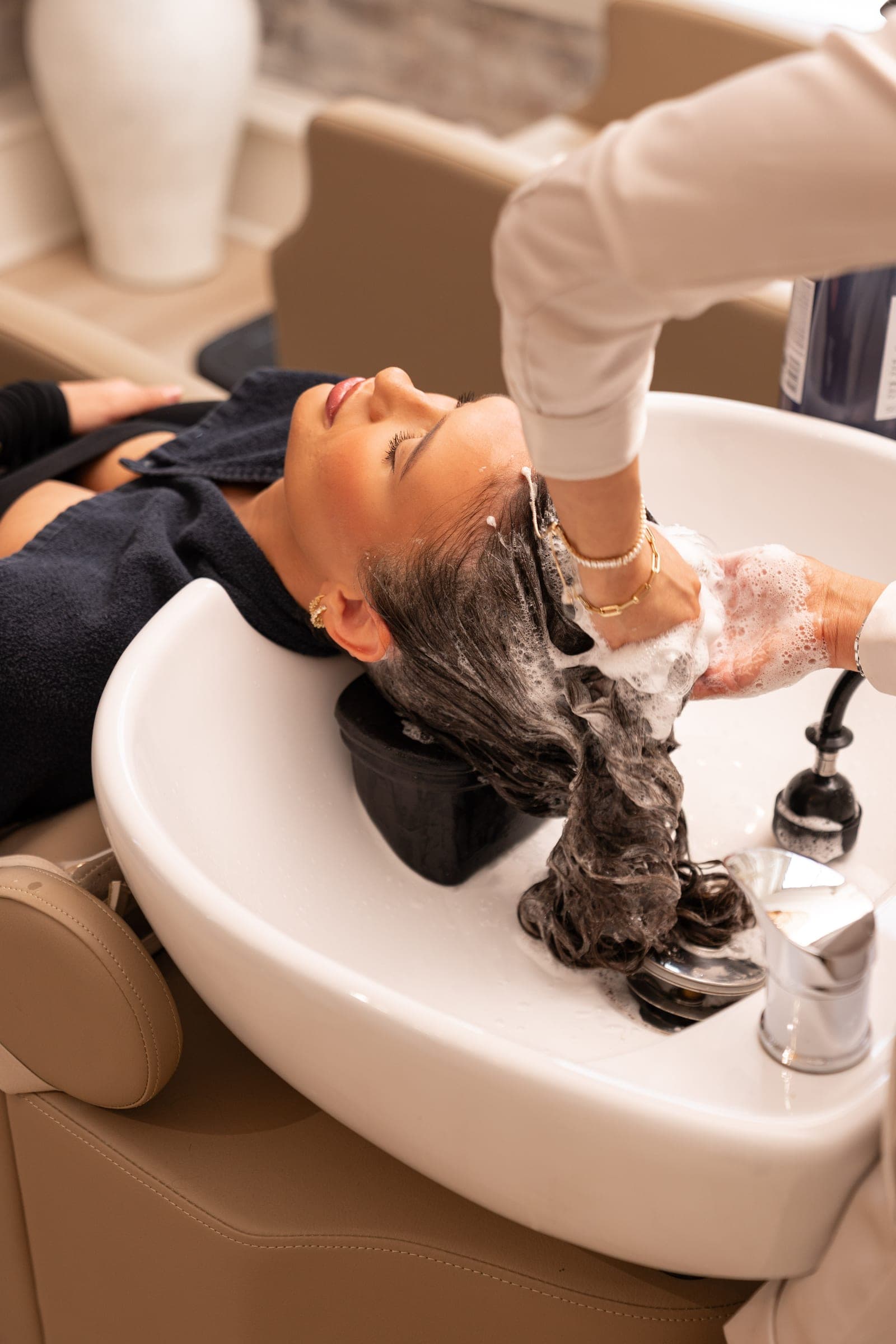 A guest reclined at the basin as their hair is lathered and massaged.