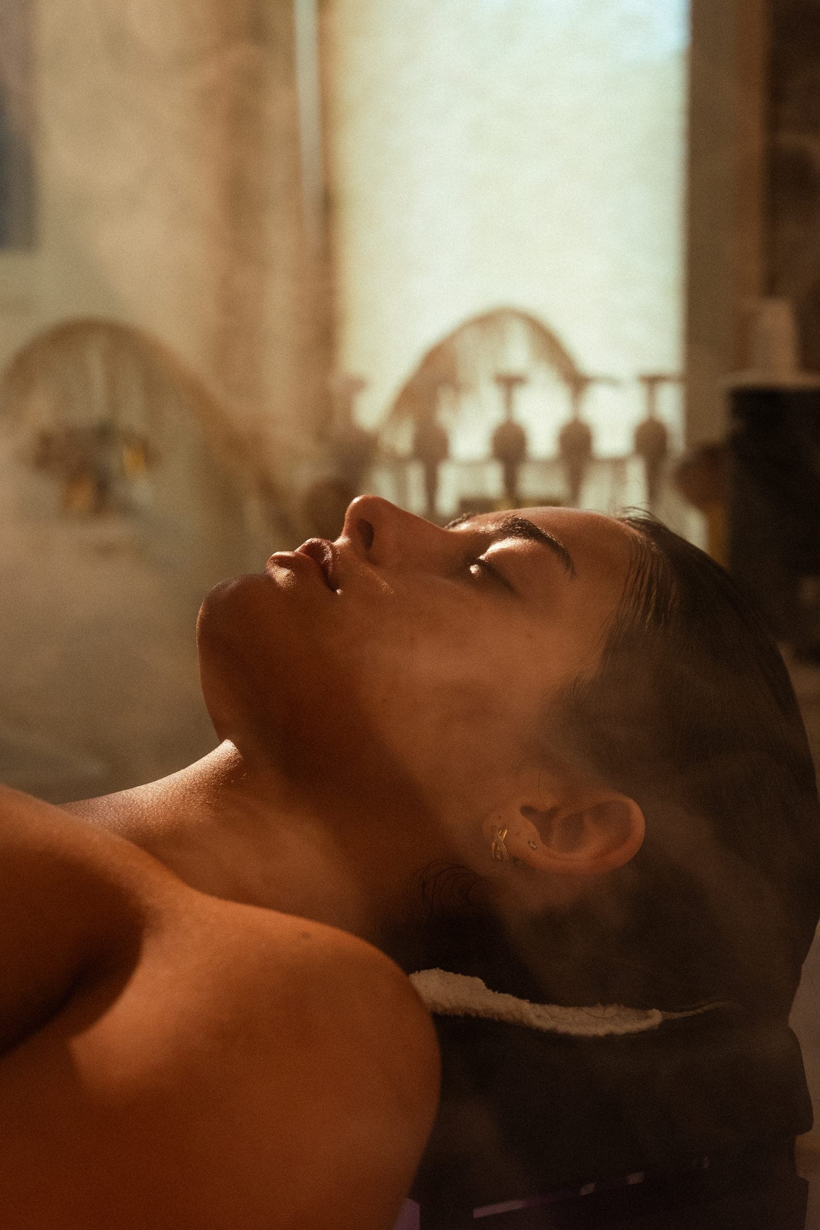 A guest reclined in the head spa, steam rising around her in warm light.
