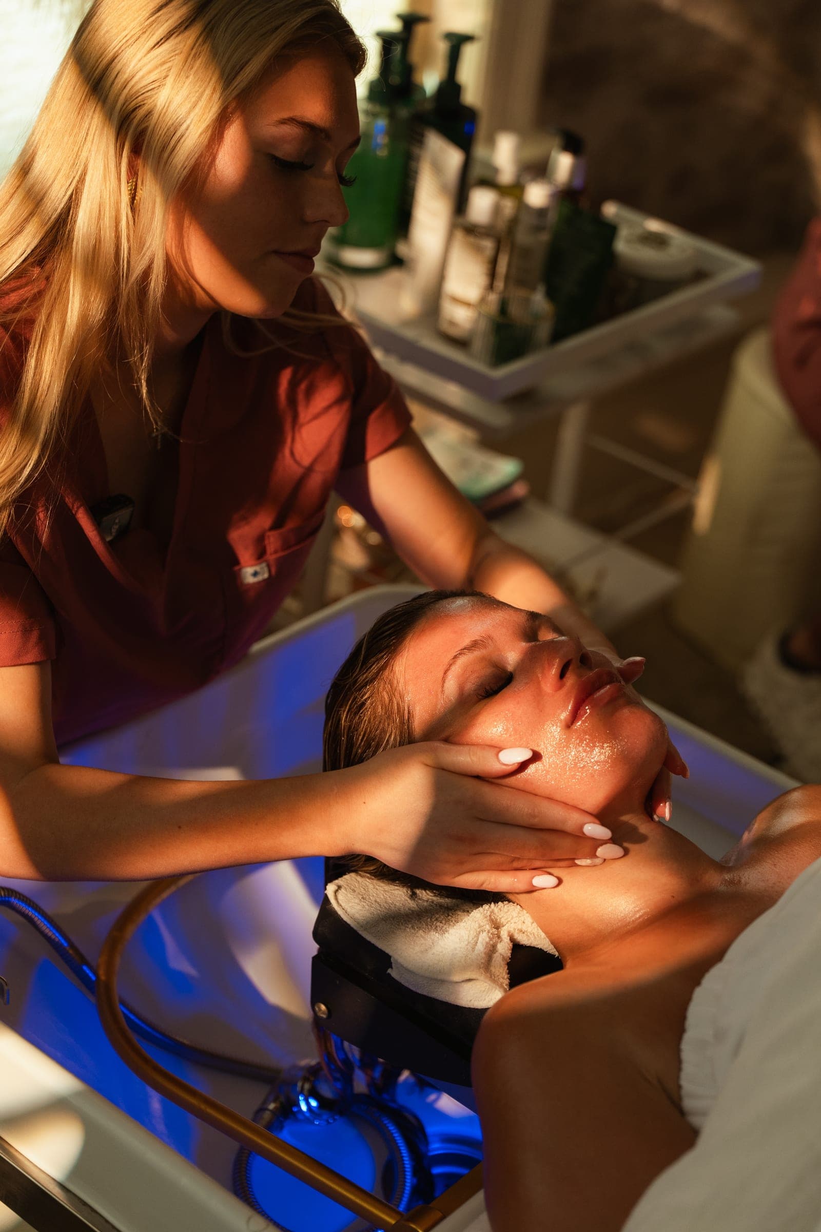 A skincare professional cleansing a guest's face during a skin ritual.