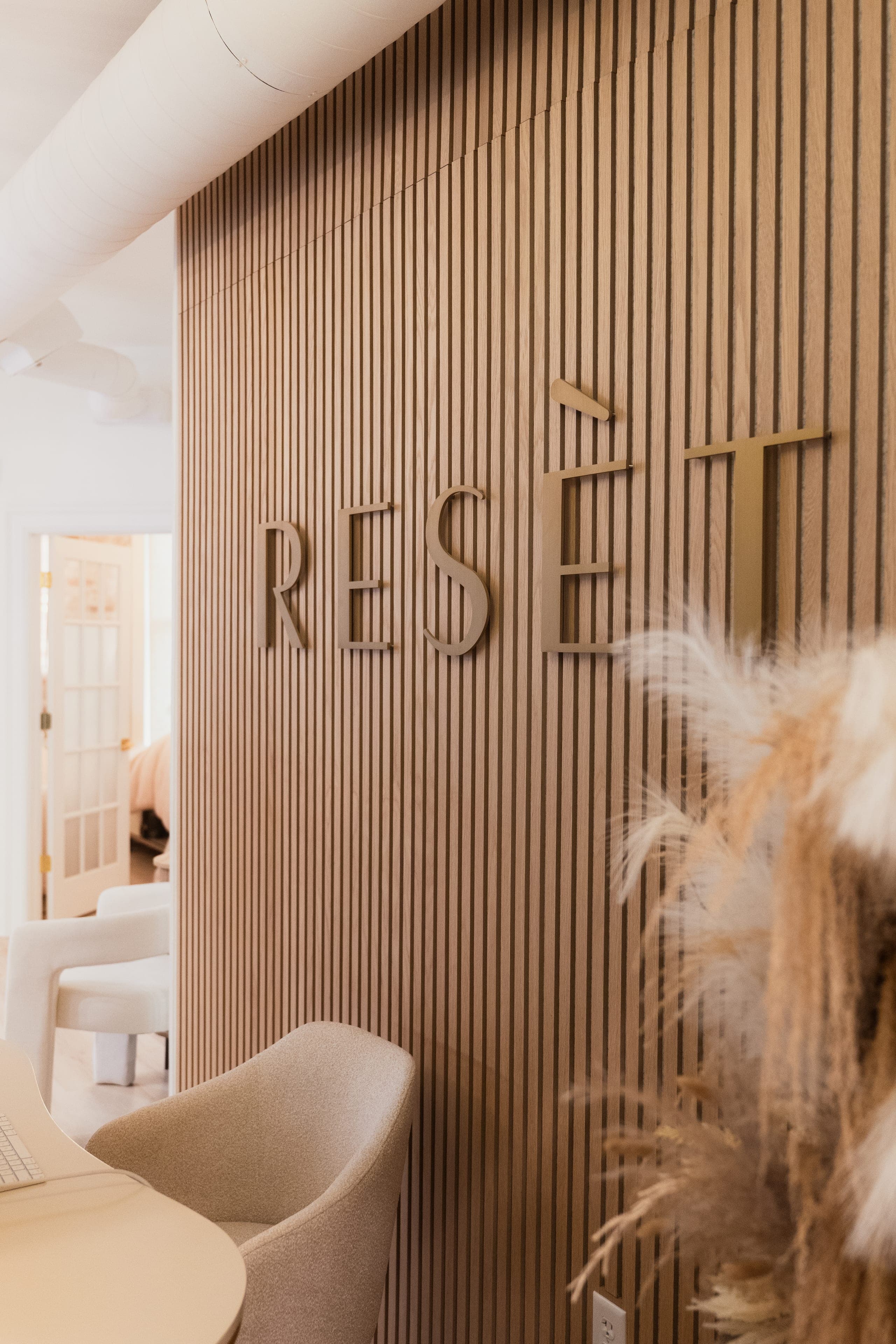 The Resèt wordmark in brass on a fluted timber wall at the entrance.